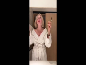 Joanna Jojo Levesque applying lipstick in bathrobe