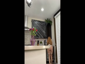 Redhead in lingerie dusts kitchen counter.