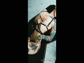 Tattooed woman in lingerie poses on black surface
