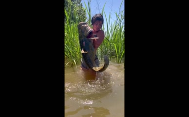 Hannah Barron in bikini top and shorts handling large catfish in water