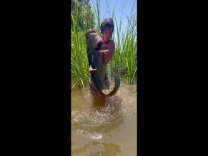 Hannah Barron in bikini top and shorts handling large catfish in water