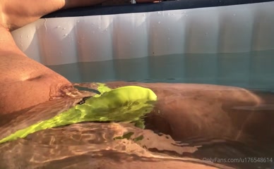Man in neon yellow speedo in hot tub.