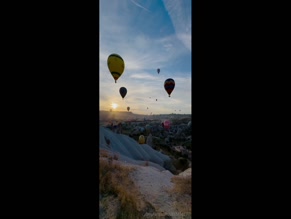 u383456197: Hot air balloons flying over scenic landscape at sunrise
